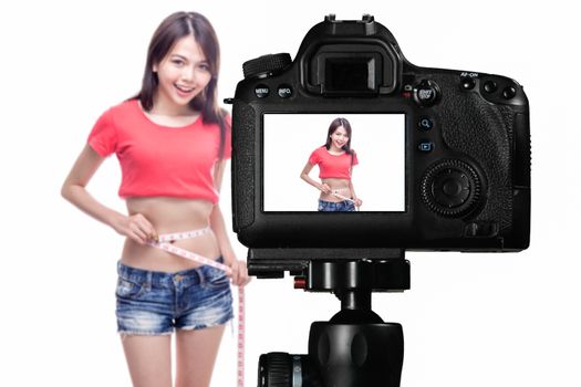 Asian vlogger measuring waist behind camera, social media production concept