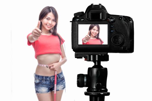 Asian vlogger measuring waist behind camera, social media production concept