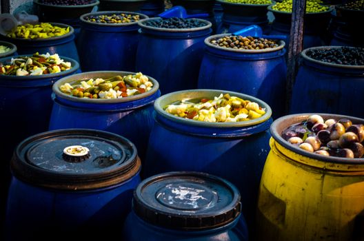 Blue barrels containing picklets, fruits, olives, cucumbers, little onions and other vegetables in a street market in Santiago de Chile