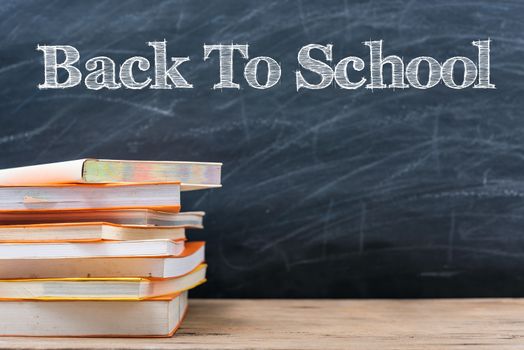 Classroom, with stack books on table have blackboard and chalkboard on background, back to school concept