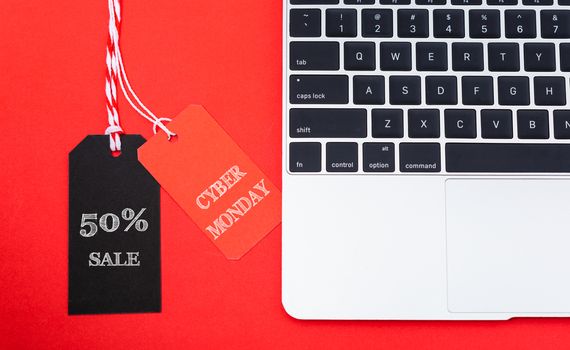 Internet online shopping marketing, top view of workspace with Cyber Monday text red and black tags near laptop computer on red background