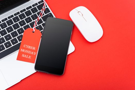 Cyber Monday Sale text on red tag have mobile smart phone over laptop computer with red background