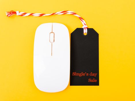 Online shopping Single's day sale text black tag on computer mouse with yellow background