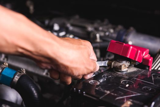 Hand of technician service check battery and turn battery screw loose in garage