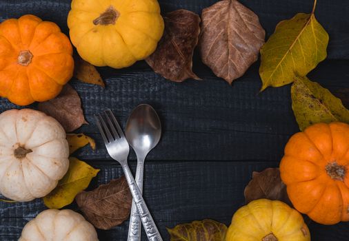 Fall Thanksgiving and Halloween pumpkins and dry leaves on wooden background, top view shot