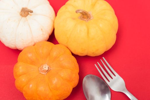 Halloween and Thanksgiving day pumpkins and leaves on red background with copy space for use