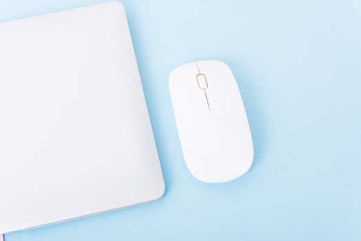 Top view close cover laptop computer notebook and wireless mouse isolated on blue background
