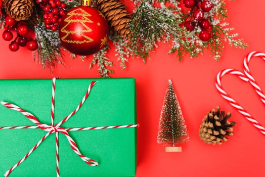 Christmas green gift box and decorations, fir tree branches on red background. Merry Christmas concept. With Copy space for text
