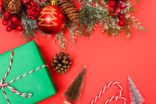 Christmas green gift box and decorations, fir tree branches on red background. Merry Christmas concept. With Copy space for text