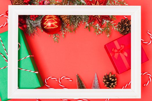 Christmas composition decorations, with white Photo frame square and fir tree branches on red background. Merry Christmas concept. Copy space for text
