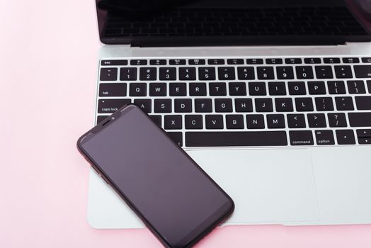 Top view of modern technology smart phone mobile and computer laptop on pink background with copy space