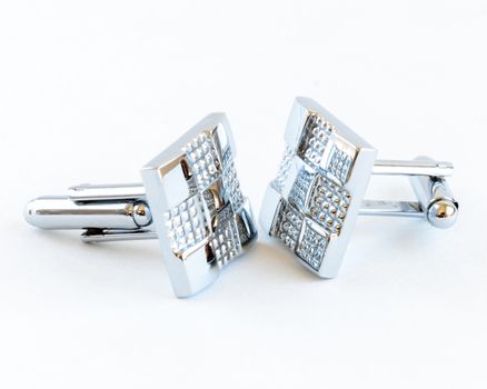Close-up single pair of modern stainless steel cufflinks isolated on white background. Lifestyle trendy clothing accessories dress with clipping path and copy space.