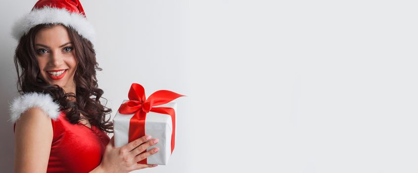 Smiling cute girl in red christmas outfit holding gift box on white background