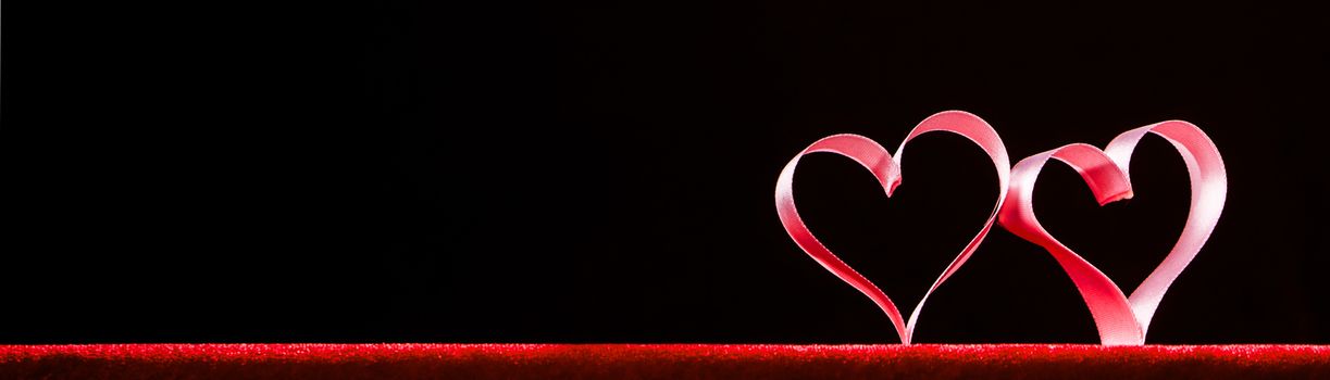 Two red ribbon hearts on black background with copy space for text, Valentines day concept