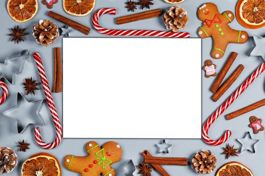 Christmas food gingerbread cookie caramel candy cane cinnamon mold shape anise orange slice on blue background with white card