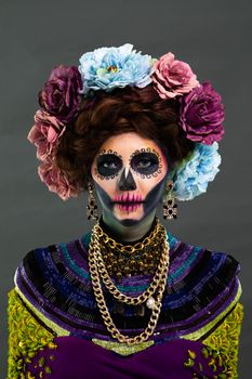 Closeup portrait of a woman with a sugar skull makeup dressed with flower crown. Halloween concept