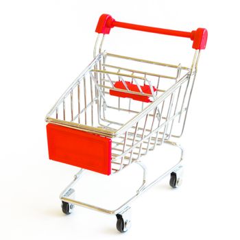 Small shopping cart isolated on white background. Tiny silver and red metallic empty push cart. Concept for online shopping and e-commerce.