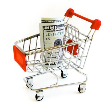 Empty small shopping cart with hundred (100) dollars banknotes inside isolated on white background. Large denominations US bill with tiny silver metallic push cart for business and currency concept