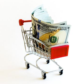 Empty small shopping cart with hundred (100) dollars banknotes inside isolated on white background. Large denominations US bill with tiny silver metallic push cart for business and currency concept