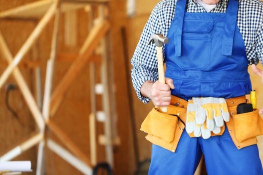 Construction worker in tool belt with hammer at construction site