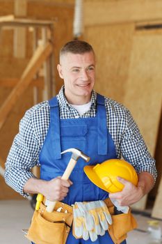 Smiling construction worker in tool belt with hammer at construction site