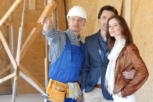 Worker in workwear shows new house from inside to a couple