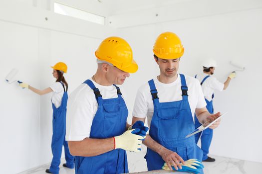 Building, construction, development, teamwork and people concept - close up of builders in hardhats working with blueprint