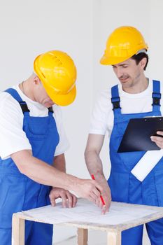 Building, construction, development, teamwork and people concept - close up of builders in hardhats working with blueprint