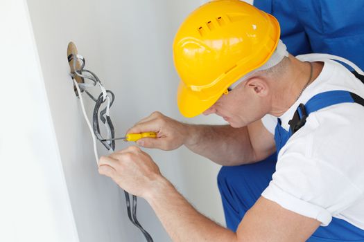 Electrician stripping electrical wires for wall socket