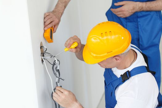 Electrician stripping electrical wires for wall socket