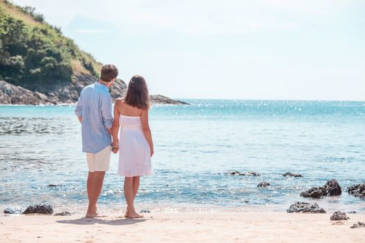 Happy couple walking on sand of tropical beach