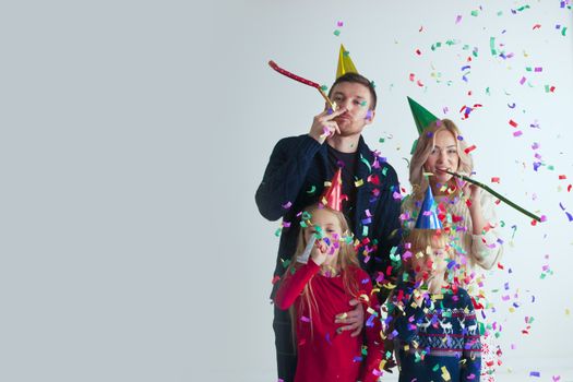 Family blowing party trumpets with confetti celebrating new year