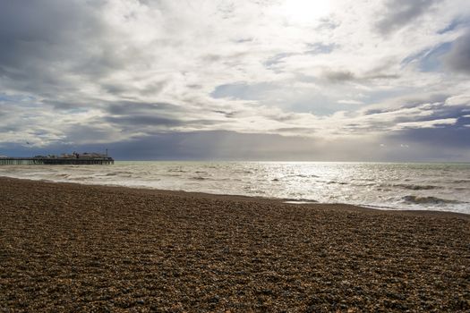 The shingle beach at Brighton, East Sussex, UK in autumn and the Brighton Palace Pier on a cloudy day, in autumn.