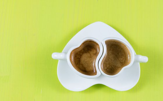 Flat lay with two cups of espresso coffee on a green wooden board. Concept for romance