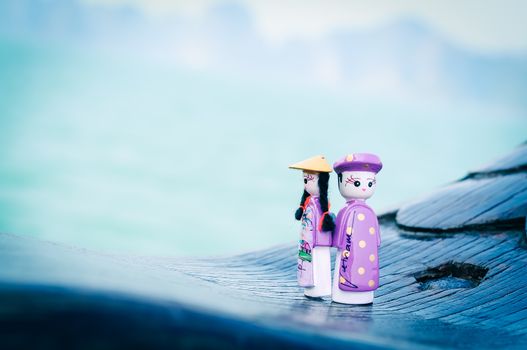 Handicraft Vietnamese magnetic wooden puppets in traditional costumes with natural ocean background. Famous Vietnamese dolls souvenirs. Selective focus on the face of the puppets