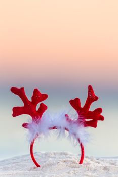 Christmas reindeer antlers on the sandy beach with background blur of ocean and sunrise sky suitable for copy space.