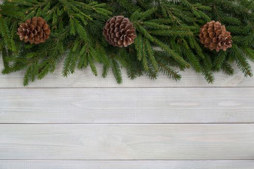 Christmas background with fir branches and cones on white toned natural wooden plank background texture provence style for copy space for text
