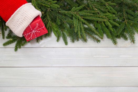 Christmas new year flat lay decor of fir branches, sock and gift on white toned natural wooden plank background texture provence style with copy space for text