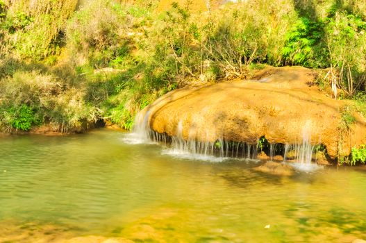 Calm spring is blocked by a round rock, limestone wall, the water is stagnant and flows back to lower bank of Dai Yem (Pink Blouse) waterfall in Muong Sang, Moc Chau, Son La, Vietnam, poetic scene