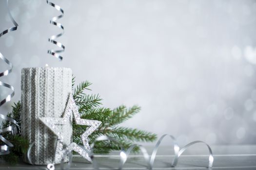 Silver Christmas new year candle with curly streamer ribbon bow decoration over glittering bokeh lights background with copy space for text