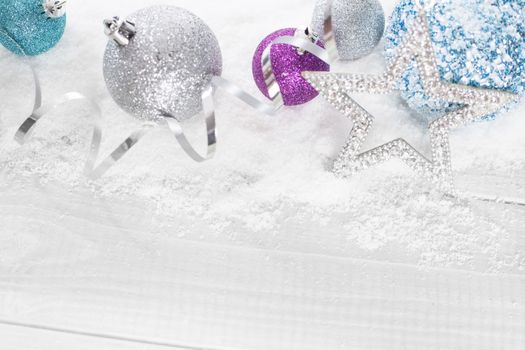 Blue and silver Christmas balls on snow on white wooden background with copy space for text