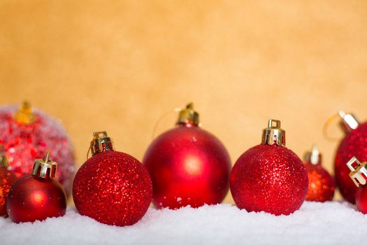 Christmas red balls on snow over golden glitter background with copy space for text