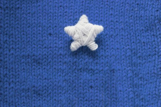 Handmade Christmas Star on blue knitted woolen background with copy space for text