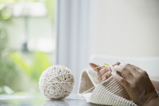 Woman's hands doing home knitting work - people with DIY work at home concept