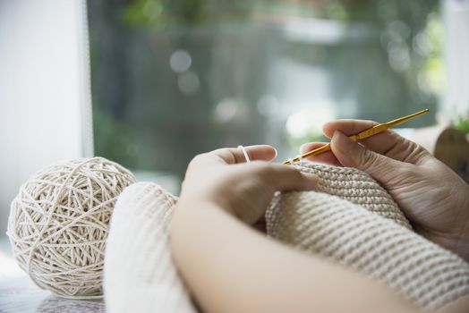 Woman's hands doing home knitting work - people with DIY work at home concept