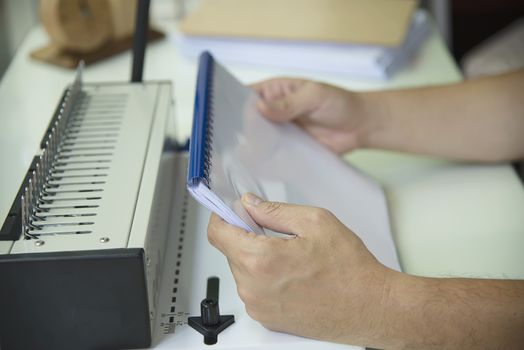 Man making report using comb binding machine - people working with stationary tools concept