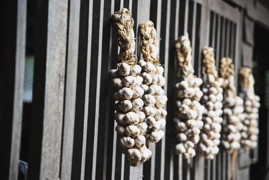 Dry garlic hanging in local kitchen wooden wall - old traditional kitchen Northern Thailand style