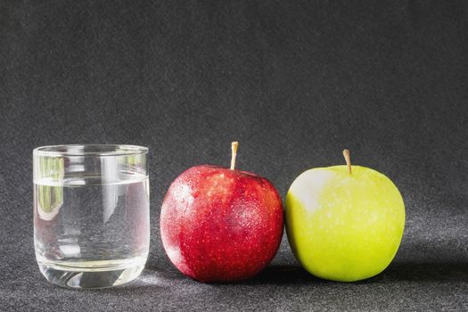 Fresh apple with glass of clean drinking water over gray background - clean fresh fruit and water background concept