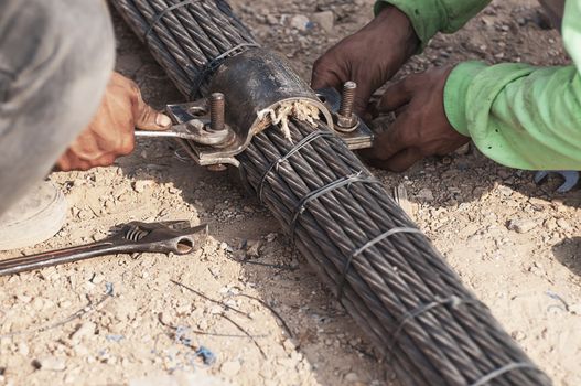 Labor man working with bridge sling tendon bolt tightening construction job - people at site construction working concept