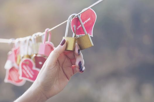 Lady hand holding padlock key with heart symbol of love on bridge - culture of love sign symbol concept